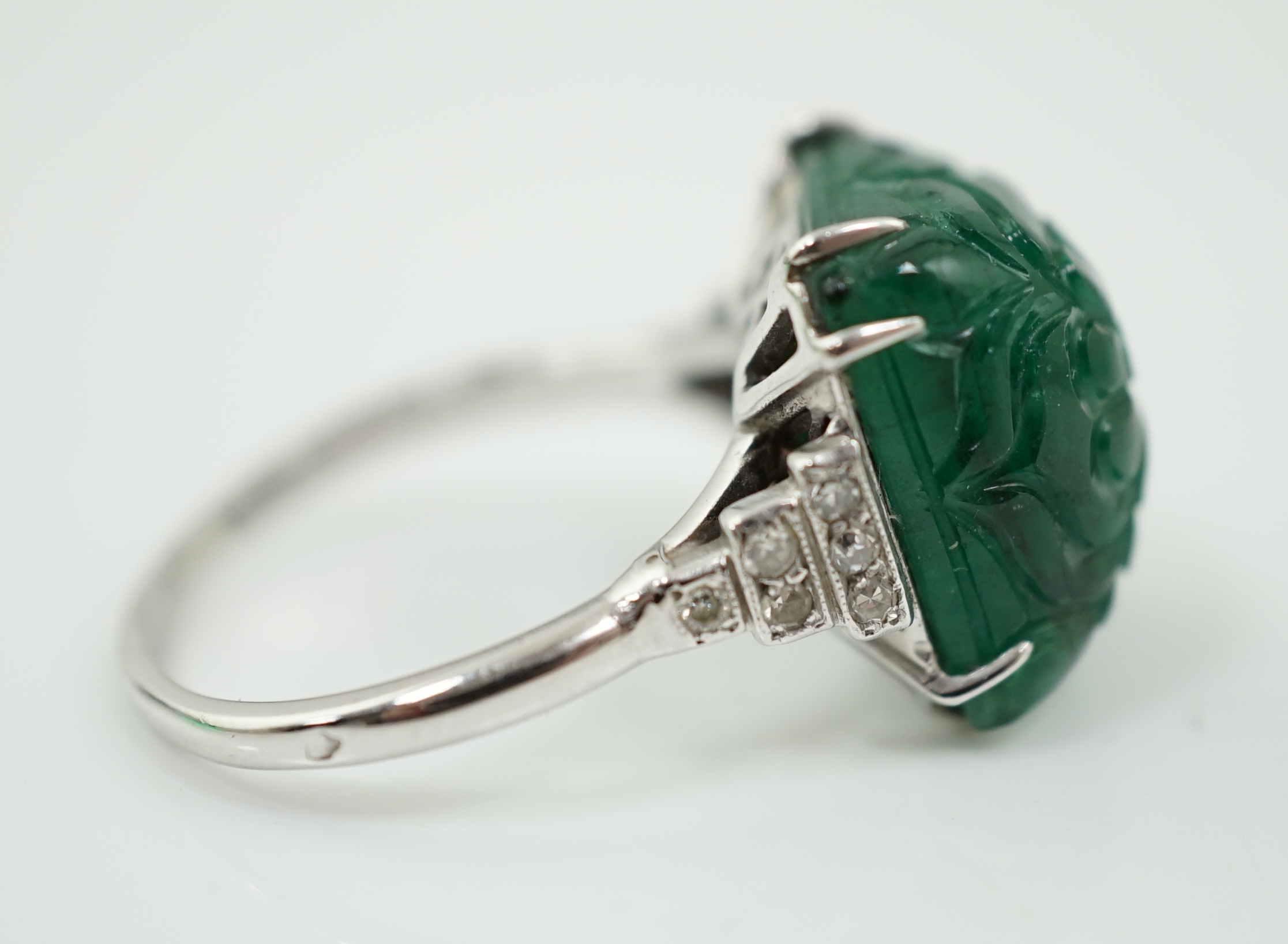 A French 1920's style platinum and single stone emerald set dress ring, with twelve stone millegrain set diamond stepped shoulders